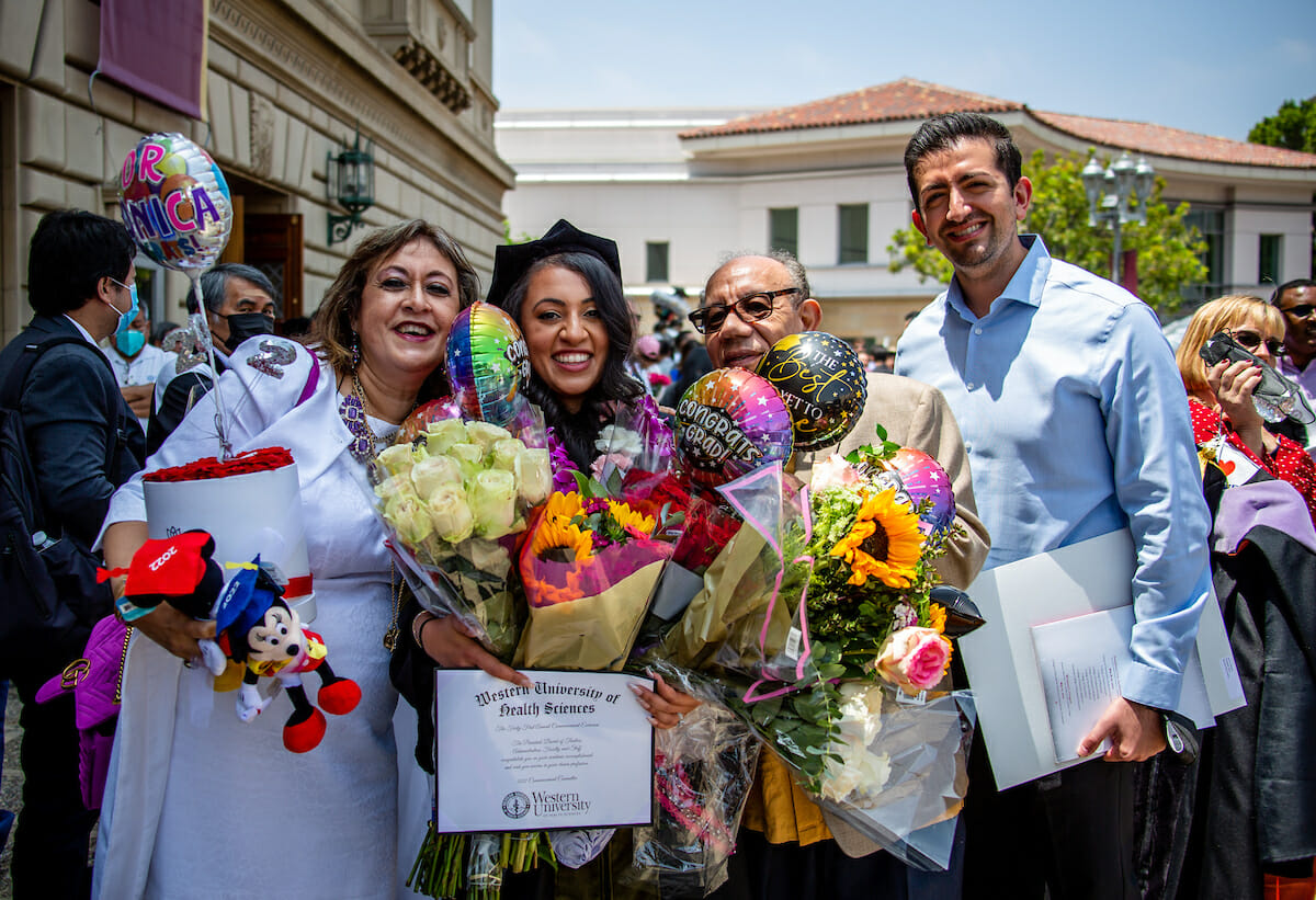 A graduate and her family holding large bouquets of flowers.