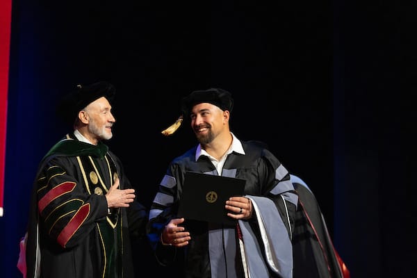 Pictured here is a graduate who has just received their stage diploma from the president and their dean and now they are making their way across stage to meet their family on stage to receive their hood.